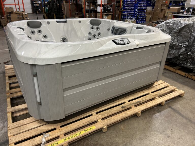 Jacuzzi J-335 hot tub front exterior view in warehouse showing gray cabinet panels and control panel