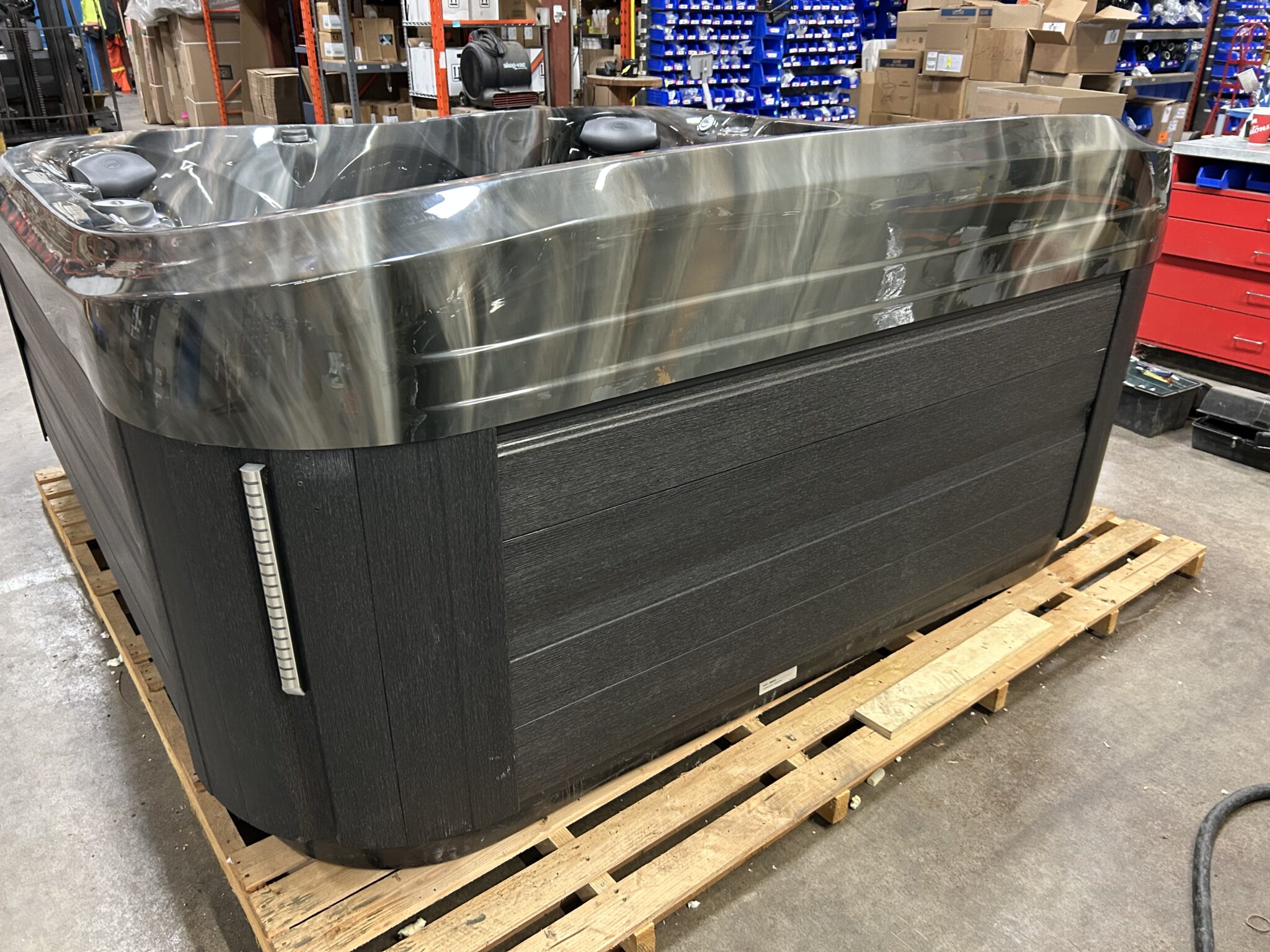 Jacuzzi J-475 hot tub rear exterior view in dark cabinet finish on warehouse floor